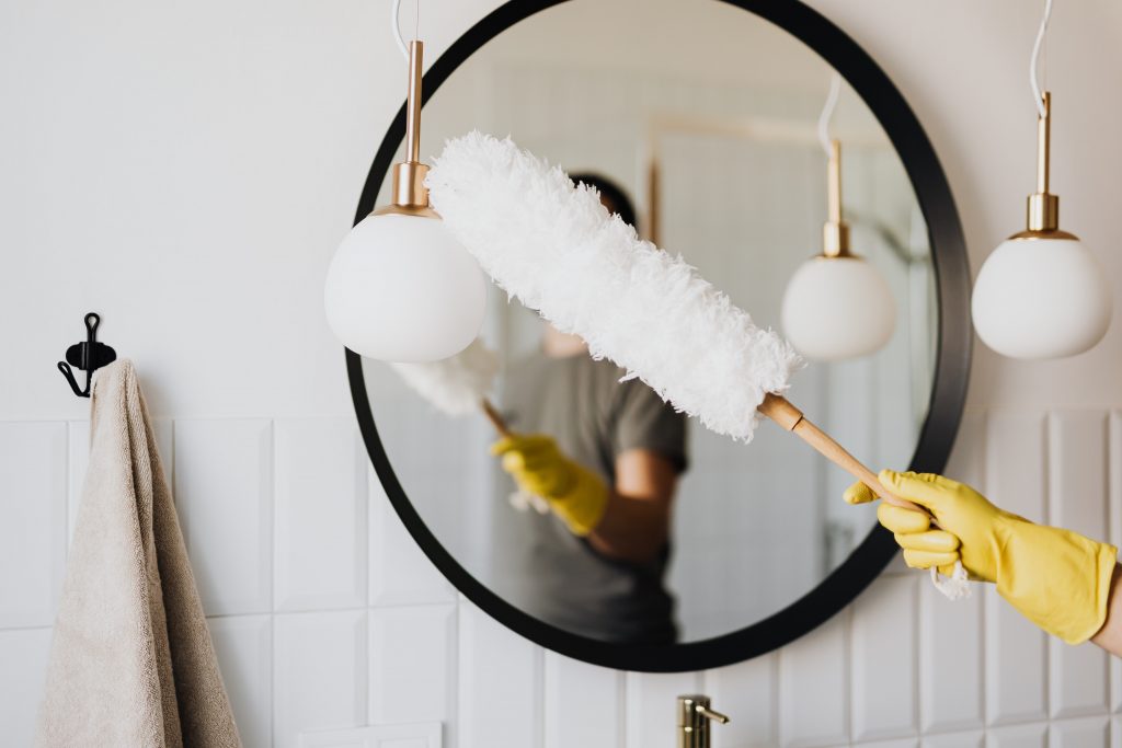 Image of a hand holding a duster next to a mirror