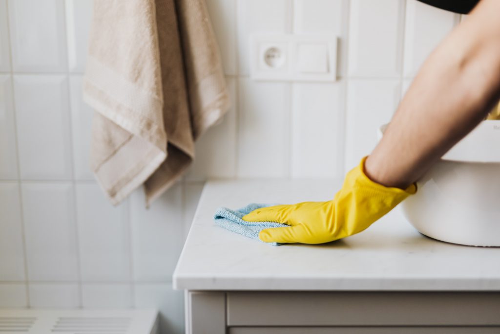 Image of a hand in a glove cleaning bathroom sink