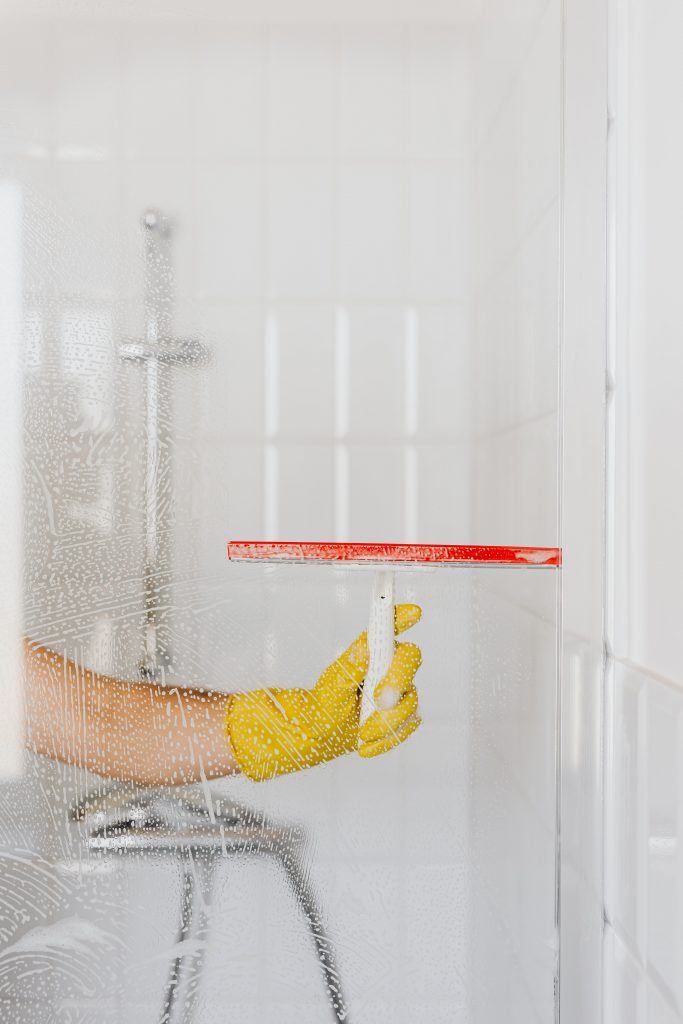 Image of a hand in a glove cleaning shower glass