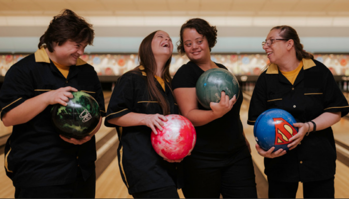Image of four women laughing playing bowling