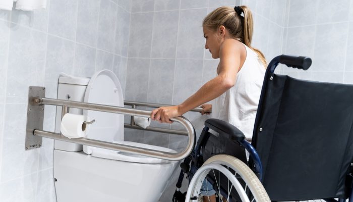 Image of woman holding rails in a handicapped toilet