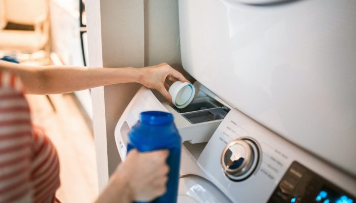Image of woman loading detergent into a washing machine